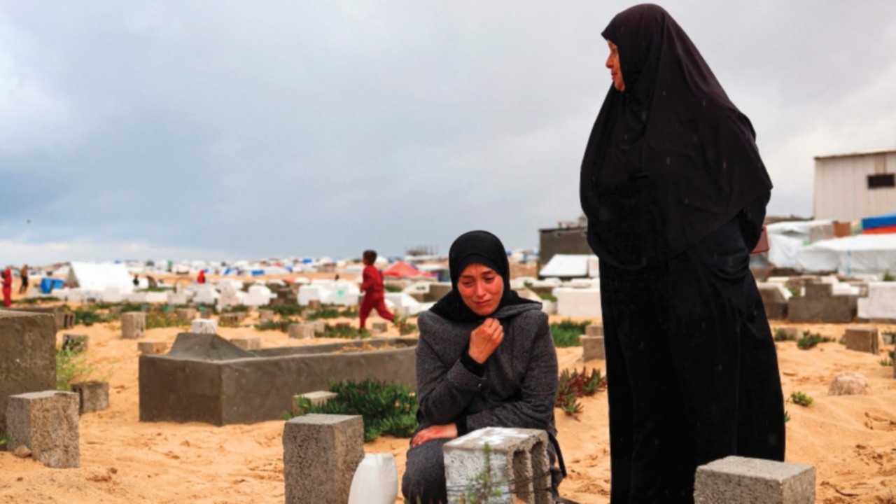 A woman cries over the grave of a loved one at the start of the Eid al-Fitr festival, marking the ...