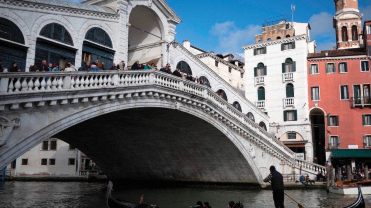 A gondola sails under the Rialto Bridge on April 24, 2024 in Venice, on the eve of the start of the ...