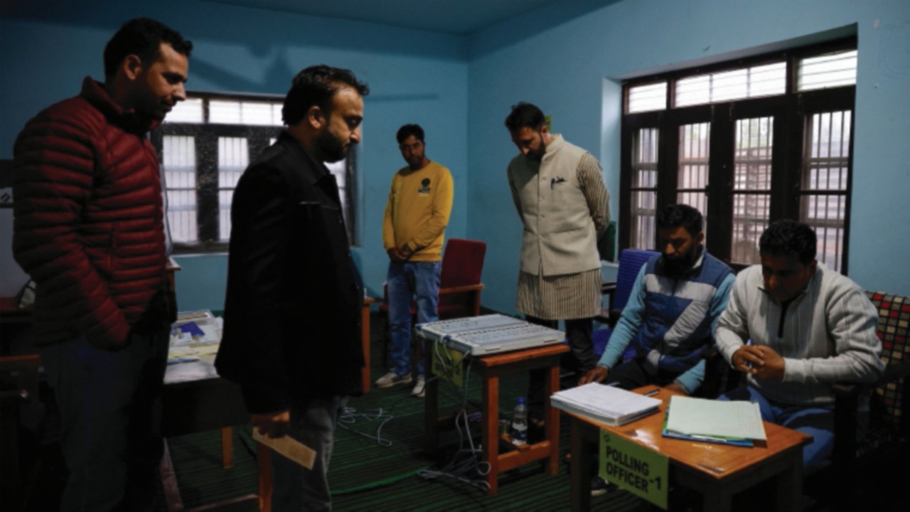Polling officers check an EVM machine inside a polling station before the voting begins, during the ...
