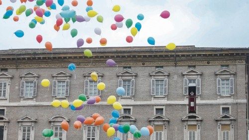 Pope Francis is framed by balloons which were released by a group of faithful during the Angelus ...