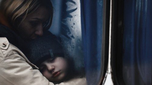 A woman and her son are seen through a bus window as they arrive at a temporary accommodation ...