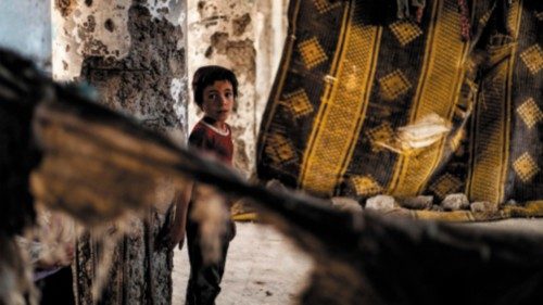 A Syrian boy, displaced with her family from Deir Ezzor, looks at the camera inside the damaged ...