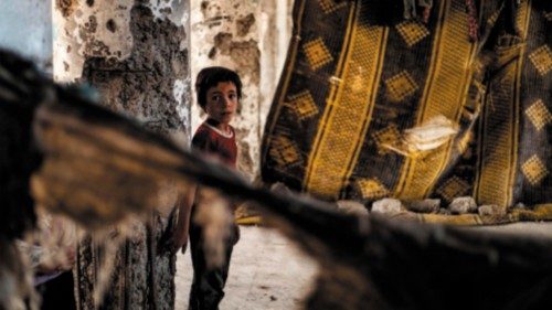 A Syrian boy, displaced with her family from Deir Ezzor, looks at the camera inside the damaged ... A Syrian boy, displaced with her family from Deir Ezzor, looks at the camera inside the damaged ...