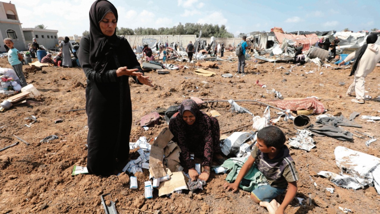 TOPSHOT - Displaced Palestinians search for items in the rubble and debris after an Israeli strike ...