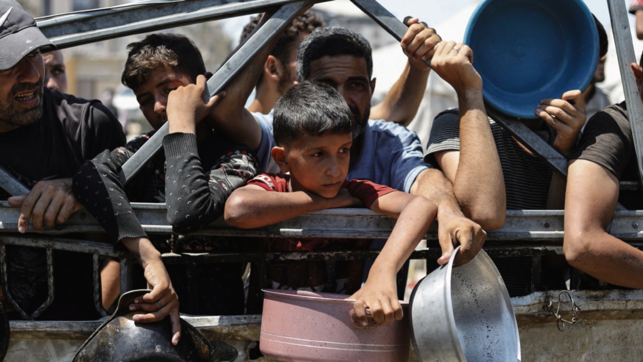 Palestinians wait to receive food from a charity kitchen, amid a hunger crisis, in Gaza City, July ...