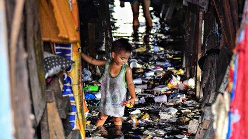 This photo taken on September 29, 2019 shows a child wading through the trash filled and polluted ...