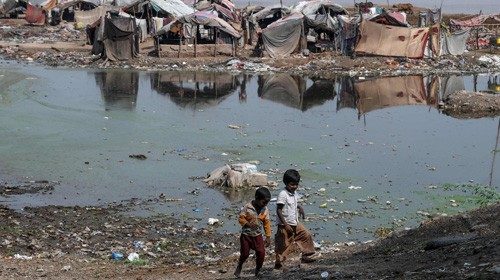 Children walk next to polluted waters in Lahore  (AFP)