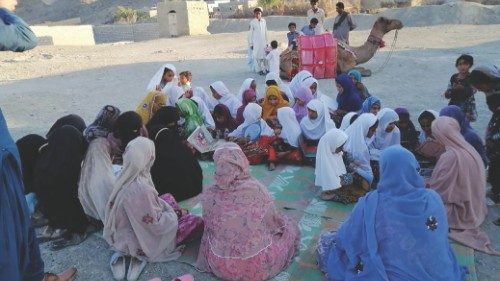 Children read books brought by Roshan the camel in Mand, Pakistan April 11, 2021. Fuzul Bashir/via ...