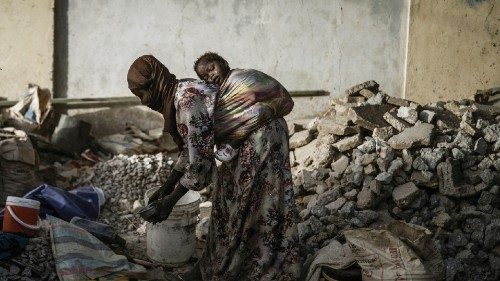 A gravel crusher carries her child on her back among slabs and smaller stones near the Cite ...