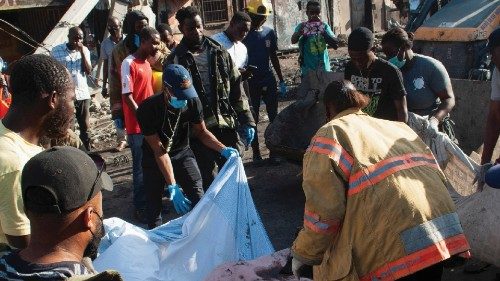 Police and firefighters wrap up the bodies of people who were killed after a fuel truck exploded in ...