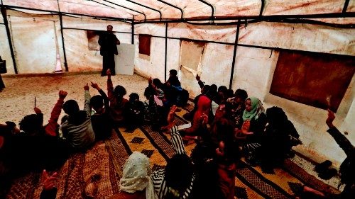 A volunteer teacher teaches students in make-shift classrooms at a camp for the displaced by the ...