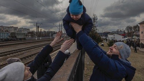 epa09801377 Oleg (R), who decided to remain in Irpin, passes his son Maksim over a fence to his wife ...