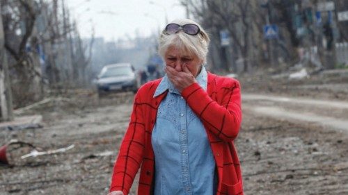A woman reacts while standing in a street, which was damaged during Ukraine-Russia conflict in the ...