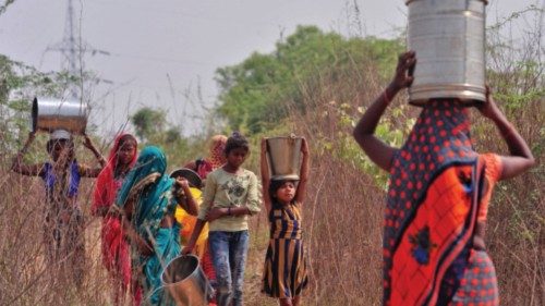 People carry water containers near an abandoned stone quarry on a hot day in Badama village in the ...