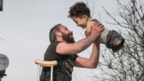 Un bambino siriano di 5 anni, nato senza braccia e gambe, immortalato sorridente con il padre, ...