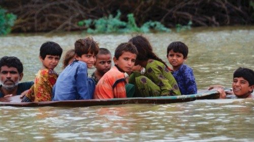 TOPSHOT - A man (L) along with a youth use a satellite dish to move children across a flooded area ...