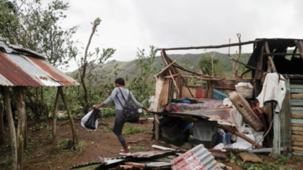 A woman removes rubble from her destroyed house in the rural zone of  Cuey, in the aftermath of ...