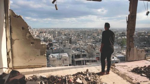 A man standing atop a heavily damaged building views other destroyed buildings in Khan Yunis in the ... A man standing atop a heavily damaged building views other destroyed buildings in Khan Yunis in the ...