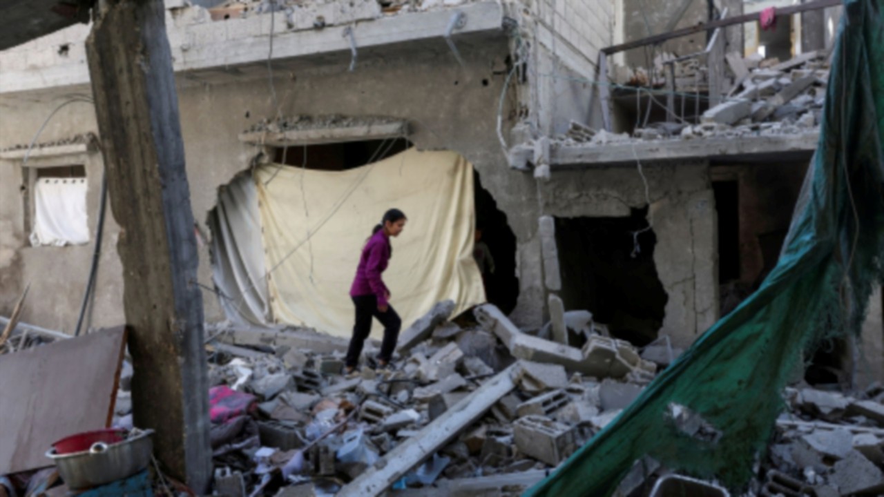 A Palestinian girl inspects the damage at the site of an Israeli strike on a house, in Deir Al-Balah ...
