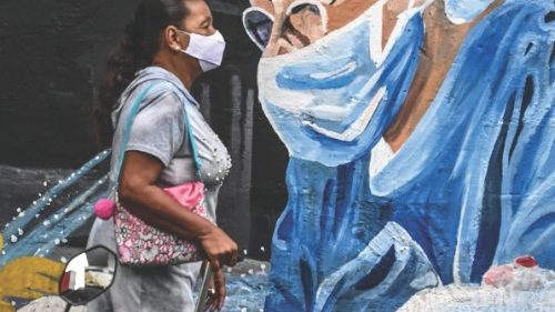 A woman walks past a COVID-19 coronavirus pandemic related-mural in Medellin, Colombia, on April 5, ...