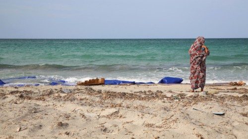 A Libyan woman stands next to the remains of a dingey and life jackets that washed up on the  beach ...