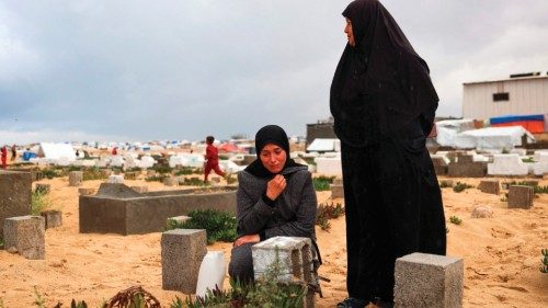 A woman cries over the grave of a loved one at the start of the Eid al-Fitr festival, marking the ...