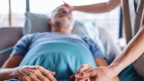 Unrecognizable female doctor examining senior man in bed in hospital, holding hands. Unrecognizable female doctor examining senior man in bed in hospital, holding hands.