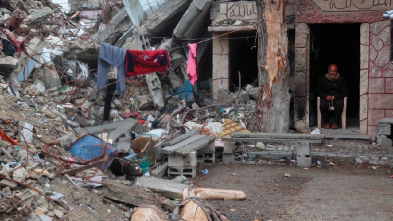 A Palestinian man sits in the doorway of a war-damaged building during the Muslim holy fasting month ...
