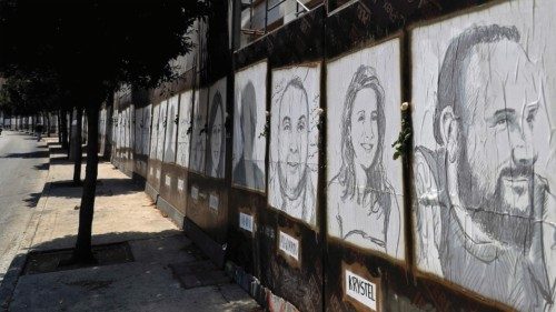 White roses are seen on portraits of victims of last year's Beirut port blast in the Lebanese ...