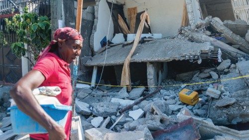 TOPSHOT - A Haitian woman cries as she passes a  destroyed house in Les Cayes on August 15, 2021, ...