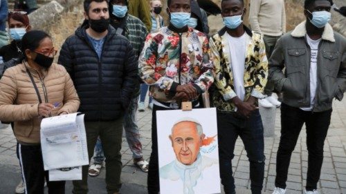 People stand near a sign with an image depicting Pope Francis, outside the Parish Church of the Holy ...