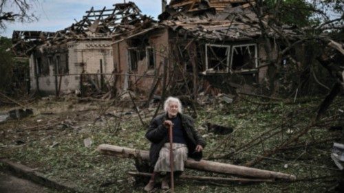 An eldery woman sits in front of destroyed houses after a missile strike, which killed an old woman, ...