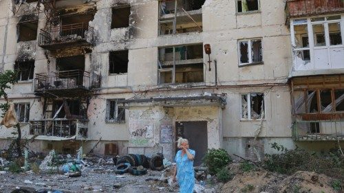 A local resident stands in front of an apartment building heavily damaged during Ukraine-Russia ...