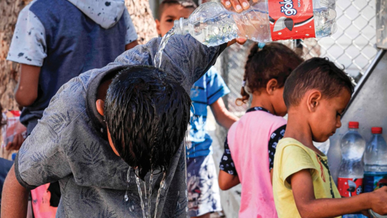 A child rinses his head with water from a bottle fresh from a cooler in Beit Lahia in the northern ...
