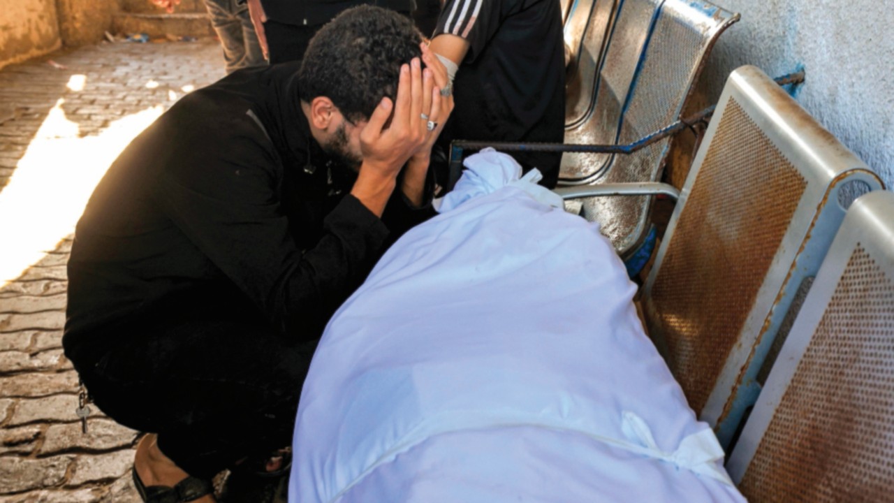 EDITORS NOTE: Graphic content / A man reacts by one of the wrapped bodies of victims who died in an ...