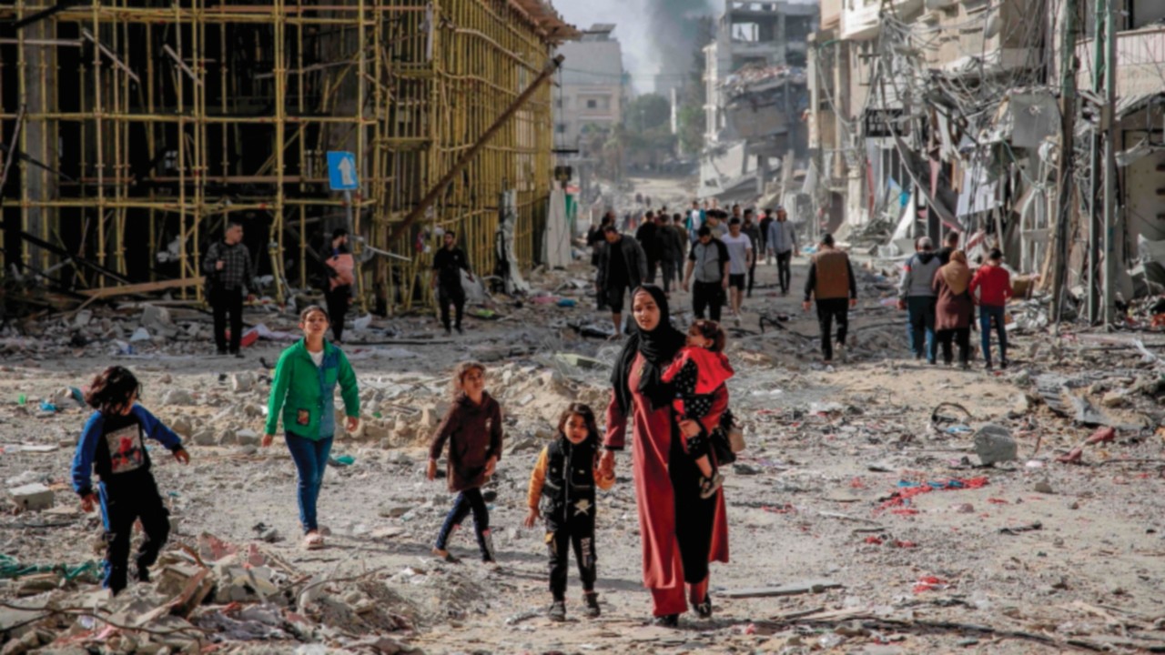 TOPSHOT - Palestinians walk amid the rubble of destroyed buildings in Gaza City on the northern Gaza ...