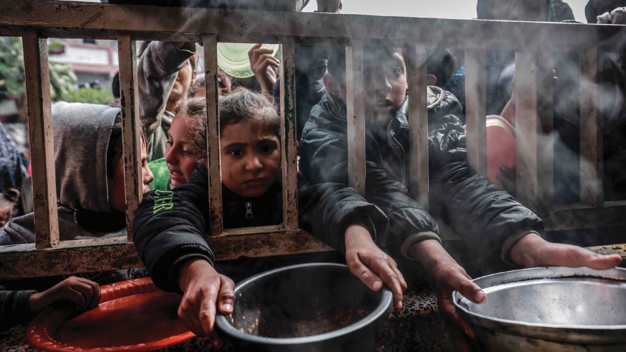 Displaced Palestinian children gather to receive food at a government school in Rafah in the ...