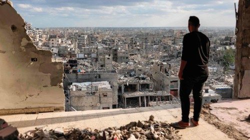 A man standing atop a heavily damaged building views other destroyed buildings in Khan Yunis in the ...