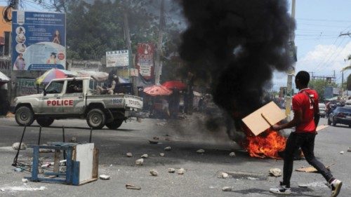 A man holds placards as he yells toward a patrol car near a burning barricade during a protest ... A man holds placards as he yells toward a patrol car near a burning barricade during a protest ...