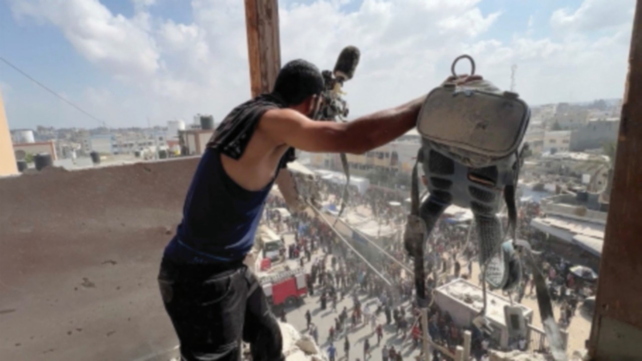 A man reacts as he holds the equipment used by Palestinian cameraman Hussam al-Masri, who was a ...