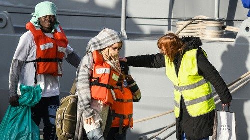 A mother and young boy, part of a group of 49 migrants, are being welcomed as they disembark from ...