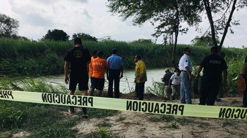 Authorities stand behind yellow warning tape along the Rio Grande bank where the bodies of ...