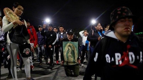 A man walks on his knees with an image of Virgin of Guadalupe towards the Basilica of Guadalupe ...