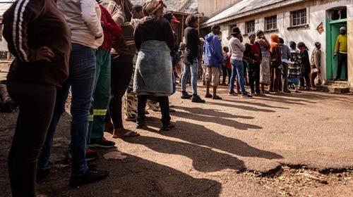 Residents of the Bekezela informal settlement stand in a queue to receive donated food by the ...