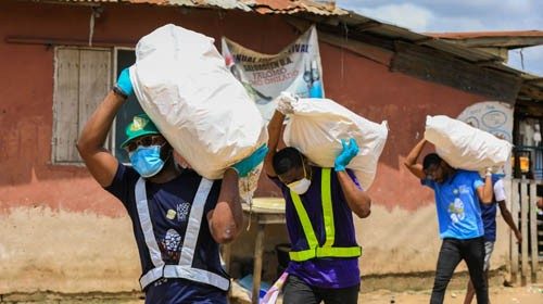 Volunteers carry sacks filled with food to distribute to vulnerable residents, during a lockdown by ...