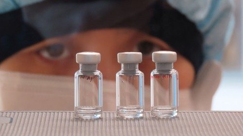 A scientist checks quality control of vaccine vials for correct volume at the Clinical ...