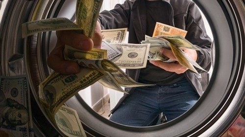 One caucasian male throwing money into a washing machinecorruzione 2.jpg