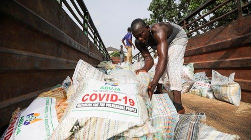 Men load sacks of rice among other food aid in a truck, to be distributed for those affected by ...