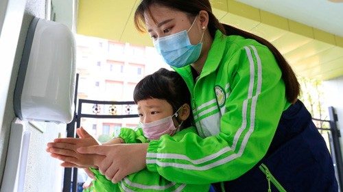 A child wearing a face mask cleans her hands at a kindergarten that has resumed operation following ...