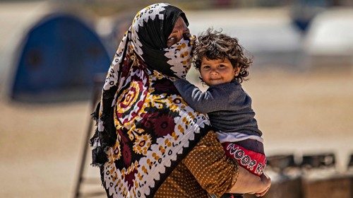 Una donna siriana con il figlio in braccio in un campo per sfollati nel nordest del Paese (Afp)